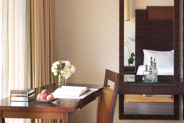 Arbeitsbereich im Zimmer des Anantara The Palm Dubai Resorts mit einem Tisch, einem Stuhl und einer Blumenvase.