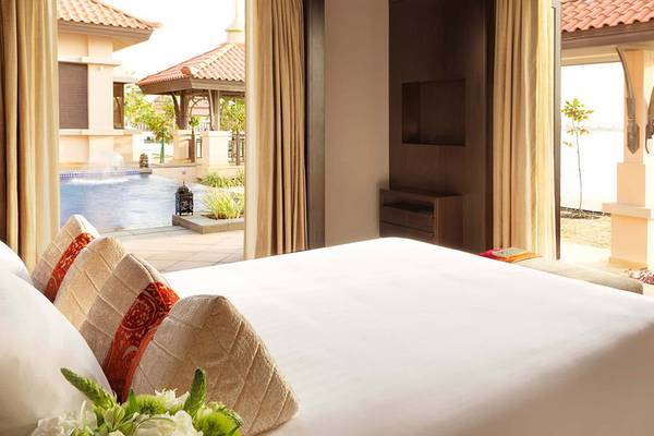 Schlafzimmer im Anantara The Palm Dubai Resort mit großem Bett und offenen Fenstern.