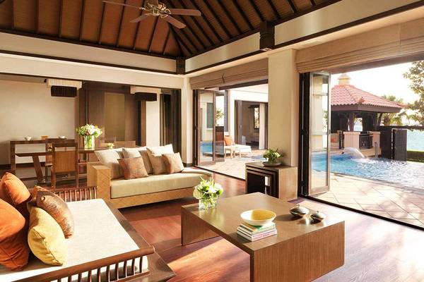 Wohnbereich im Anantara The Palm Dubai Resort mit großer Glaswand, die auf einen Swimmingpool und eine Aussicht aufs Meer hinausblickt.
