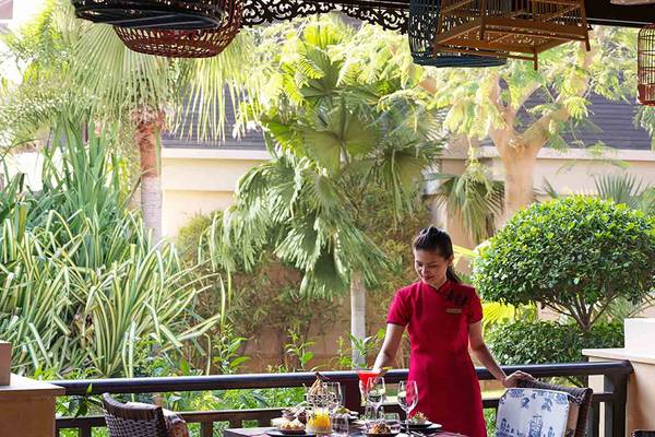 Eine Frau in einem roten Kleid serviert auf einer Terrasse des Anantara The Palm Dubai Resorts.