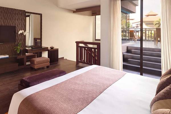 Innenansicht eines Hotelzimmers im Anantara The Palm Dubai Resort mit Bett, Fernseher, Schreibtisch und Balkon.
