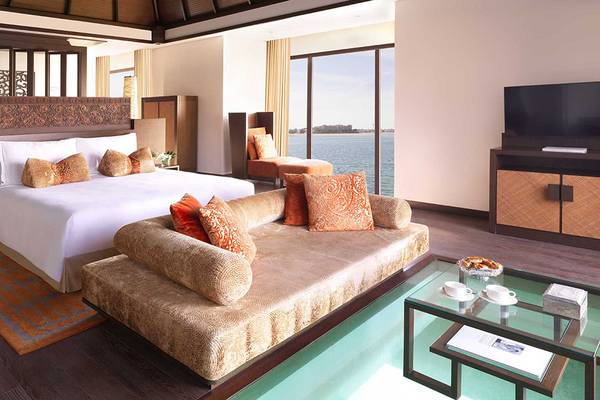 Innenansicht eines eleganten Schlafzimmers im Anantara The Palm Dubai Resort mit einem großen Bett, einem Wohnzimmerbereich und einem beeindruckenden Meerblick.