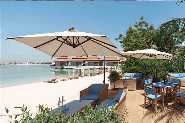 Außensitzplatz am Strand des Anantara The Palm Dubai Resorts mit Tischen und Stühlen unter Sonnenschirmen