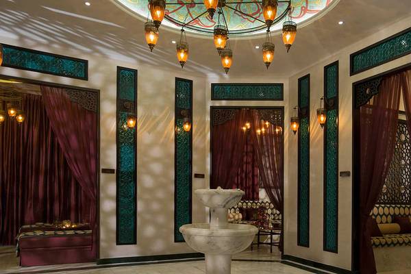 Innenbereich des Anantara The Palm Dubai Resorts mit Brunnen, roten Vorhängen und türkisfarbenen Akzenten.
