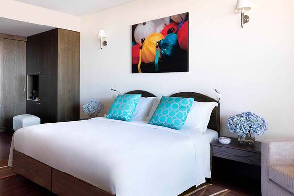 Schlafzimmer im Anantara The Palm Dubai Resort mit großem Bett, bunten Kissen und Gemälde an der Wand.