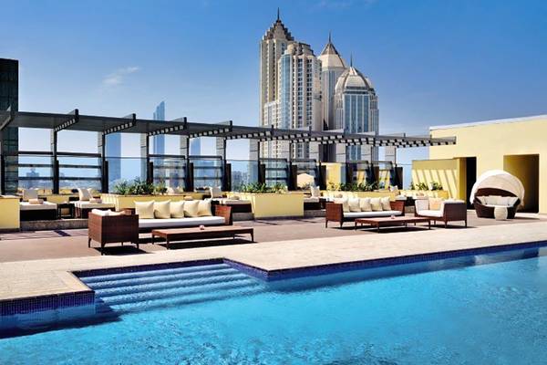 Außenpoolbereich des Southern Sun Abu Dhabi mit Loungemöbeln und Blick auf die Skyline.
