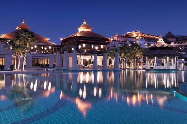 Ein Swimmingpool mit blauem Wasser, reflektiert in der Nacht, vor dem Anantara The Palm Dubai Resort.
