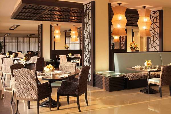 Restaurant im Anantara The Palm Dubai Resort mit Tischen, Stühlen und dekorativen Lampen.