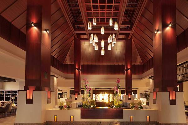 Empfangsbereich des Anantara The Palm Dubai Resorts mit hohen Decken, roten Säulen und einer zentralen Feuerstelle.