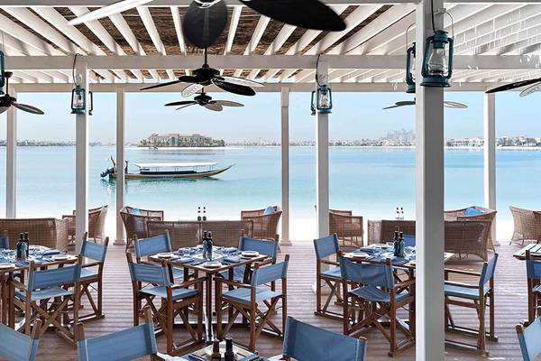 Innenansicht eines Restaurants im Anantara The Palm Dubai Resort mit Blick auf das Meer und eine Insel.