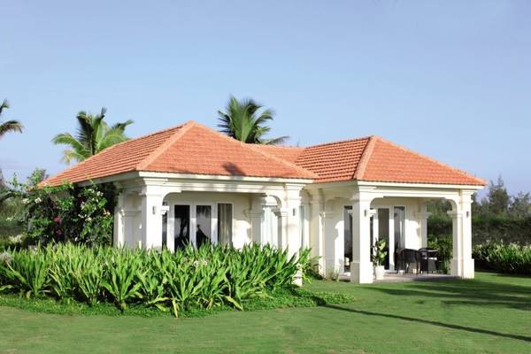 Außenansicht des Boutique Hoi An Resorts mit grünem Rasen und roten Dächern