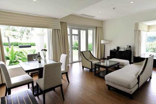 Wohnbereich des Boutique Hoi An Resorts mit moderner Einrichtung, großen Fenstern und Blick auf den Garten.