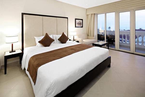 Hotelzimmer im Boutique Hoi An Resort mit Bett, Lampen, Tisch, Sofa und Terrassentür.