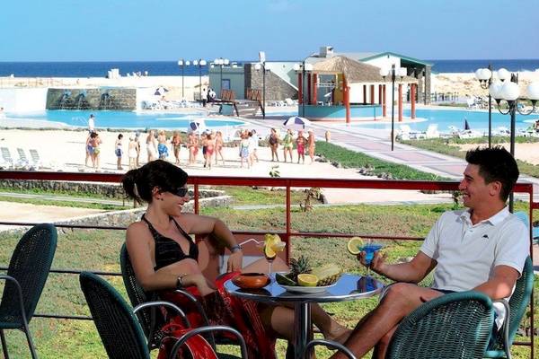 Paar genießt Cocktails auf der Terrasse des VOI Vila Do Farol Resorts mit Blick auf den Pool.
