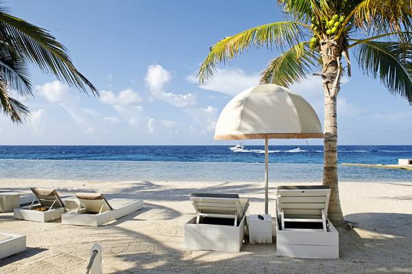 Strand des Morena Eco Resorts mit weißen Liegen und Sonnenschirmen am Meer