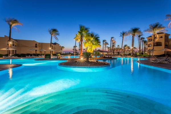 Cleopatra Luxury Beach Resort Pool bei Nacht mit Palmen und Lounge-Stühlen