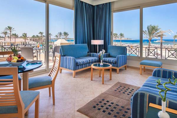 Innenansicht eines Luxus-Strandhotels mit Blick auf das Meer, blaue Möbel und Glasfenster.