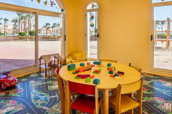 Spielzimmer im Cleopatra Luxury Beach Resort mit gelbem Tisch, Legos und Straßenteppich.