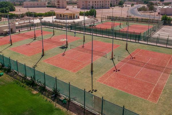 Luftaufnahme der Tennisanlage im Cleopatra Luxury Beach Resort mit roten Tennisplätzen und Gebäuden im Hintergrund.