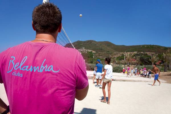 Rückansicht eines Mannes in einem rosa Belambra Clubs T-Shirt, der auf ein Volleyballspiel blickt.