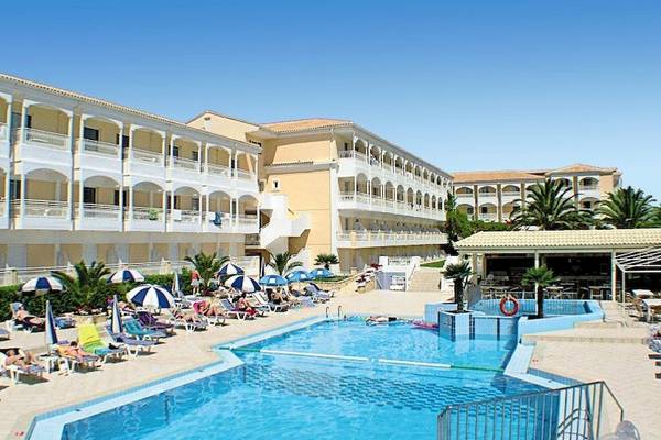 Poseidon Beach Hotel Außenbereich mit Pool, Gäste entspannen auf Sonnenliegen und unter Sonnenschirmen.