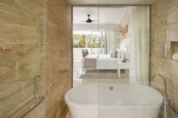 Badezimmer im Melia Caribe Beach Resort mit Badewanne, Dusche und Blick auf das Schlafzimmer.