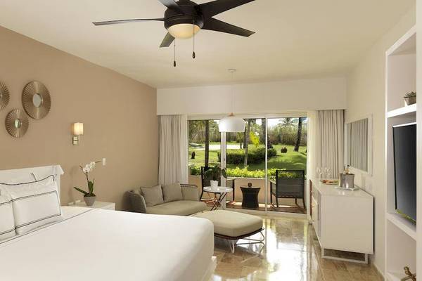 Luxuriöses Zimmer im Melia Caribe Beach Resort mit Bett, Sofa, Klimaanlage und Gartenblick.