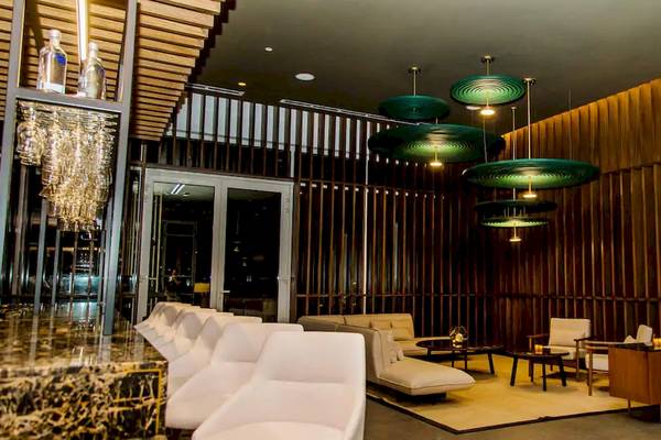 Das geräumige Lounge- und Barbereich des Melia Caribe Beach Resort mit weißen Möbeln, Holzwänden und grünen Hängelampen.