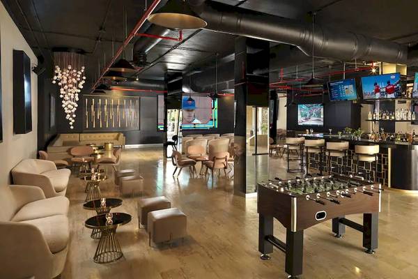 Loungebereich des Melia Caribe Beach Resorts mit Fernsehern, Bar, Fußballtisch und Möbeln.