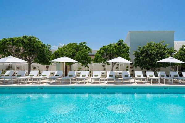 Außenpoolbereich des Melia Caribe Beach Resort mit weißen Liegen und Sonnenschirmen.