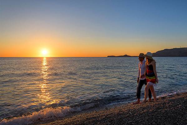 Paar genießt Sonnenuntergang am Strand des Atrium Palace Thalasso Spa Resort & Villas.