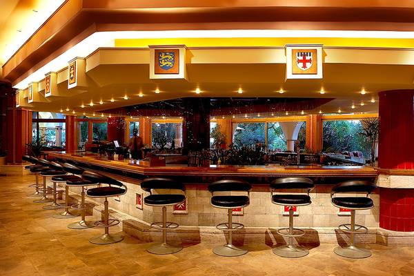 Innenansicht der Bar des Atrium Palace Thalasso Spa Resort & Villas mit Barhockern und einer Theke.
