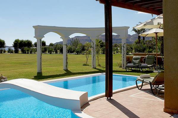 Außenpool des Atrium Palace Thalasso Spa Resort & Villas mit Blick auf eine große Wiese und eine Berglandschaft.