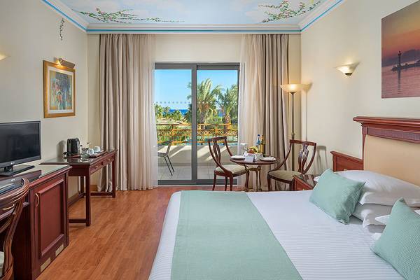Hotelzimmer mit Balkon und Meerblick, ausgestattet mit Fernseher, Schreibtisch, Sessel und Tisch.
