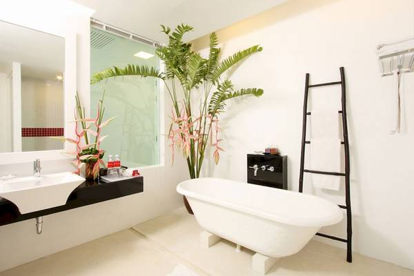 Das Badezimmer im Hotel The Old Phuket - Karon Beach Resort mit einer Badewanne, Waschbecken, Spiegel und Pflanzen.