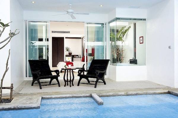 Sitzecke mit zwei Sesseln und kleinem Tisch neben dem Pool im Hotel The Old Phuket