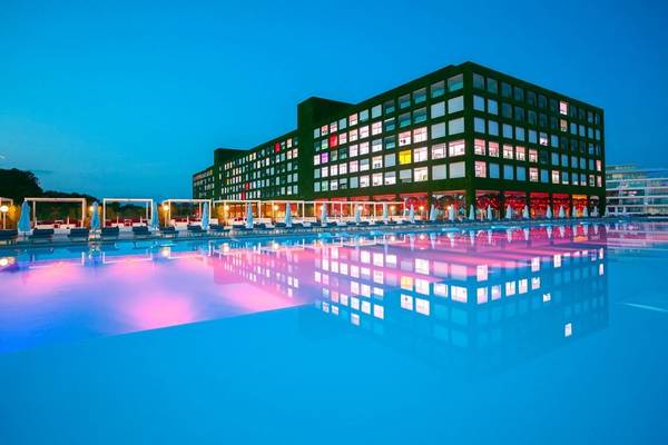 Nachtansicht des Außenpools des Adam & Eve Hotels mit illuminiertem Gebäude im Hintergrund.