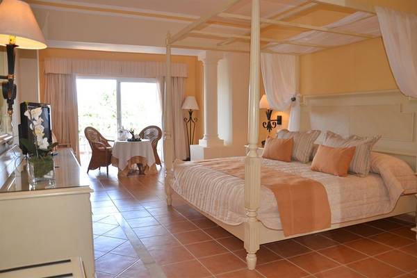 Schlafzimmer im Bahia Principe Grand Jamaica Hotel mit vierpfostenbett und Tageslicht.