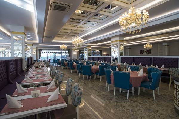 Innenansicht des Restaurants im Dream World Aqua Hotel mit blauen Stühlen und runden Tischen.