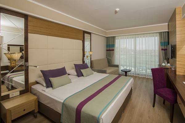 Dream World Aqua Hotel Zimmer mit Doppelbett, Möbeln und Fenstern mit Vorhängen.