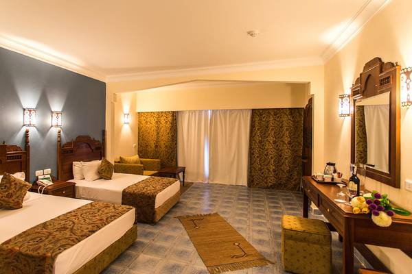 Doppelzimmer im Jasmine Palace Resort & Spa mit zwei Betten, Sofa, Schreibtisch, Spiegel und Fenstern.