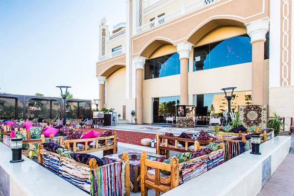 Außenbereich des Jasmine Palace Resort & Spa mit bunten Sofas und Kissen, umgeben von Pflanzen und Lampen.