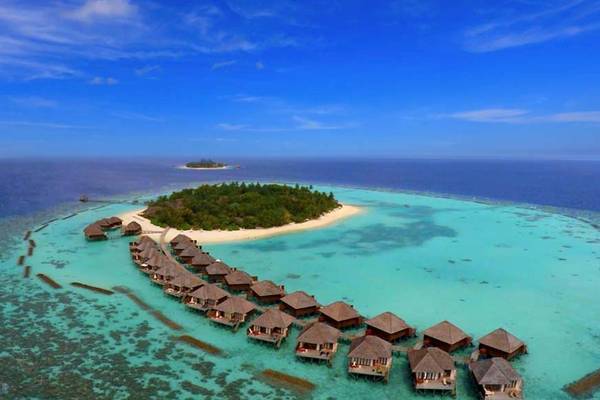 Luftaufnahme des Nova Maldives Resorts mit vielen Hütten am Wasser und einer kleinen Insel im Hintergrund.