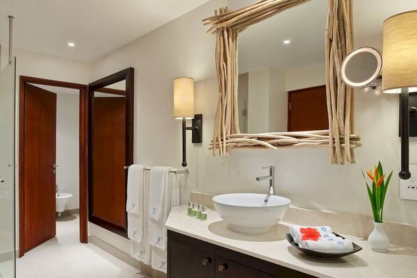 Badezimmer im Kempinski Seychelles Resort mit Dusche, Waschbecken und Spiegel.
