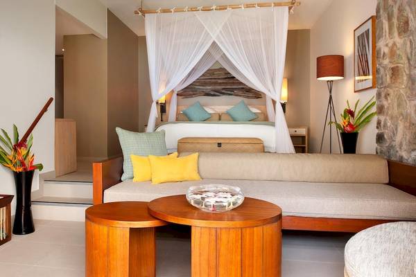 Zimmer im Kempinski Seychelles Resort mit Bett, Couch, Tisch und Dekor.