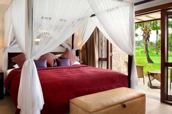 Bett im Kempinski Seychelles Resort mit rotem Bettlaken und weißem Baldachin