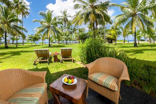 Gartensitzplatz des Kempinski Seychelles Resort mit Korbstühlen und einem Tisch mit Obstteller.