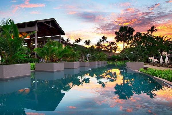 Sonnenuntergang im Kempinski Seychelles Resort mit Swimmingpool und Pflanzen.