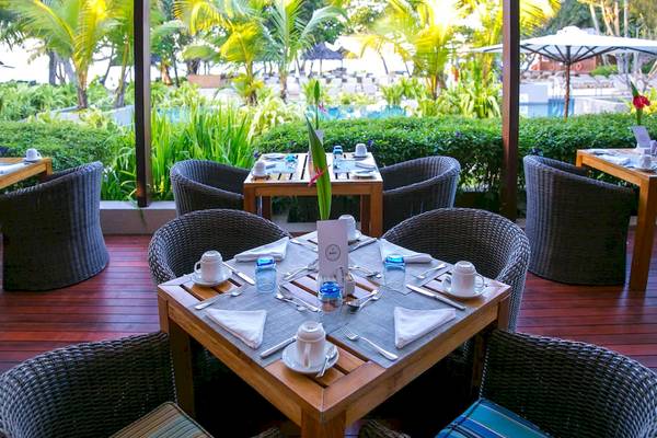 Außensitzplatz im Kempinski Seychelles Resort mit Blick auf einen Pool und Palmen