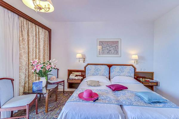 Doppelbett-Zimmer im Creta Royal - Adults Only Hotel mit Blumenvase und Hut auf dem Bett.